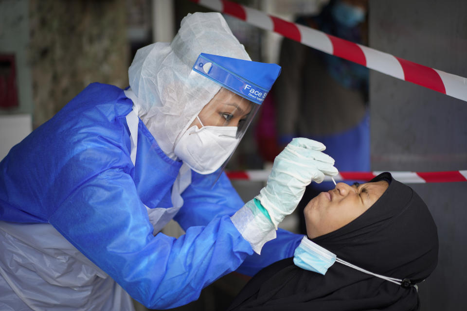 A doctor collects a sample for a coronavirus test at a clinic in Puchong on the outskirts of Kuala Lumpur, Malaysia, Tuesday, Oct. 6, 2020. Virus cases in Malaysia spiked to a new daily record high of 691 on Tuesday, with four new deaths including a one-year-old baby. Prime Minister Muhyiddin Yassin said there will not be another national lockdown as this will crush the economy, but measures will be targeted to curb transmission in hotspot zones. (AP Photo/Vincent Thian)