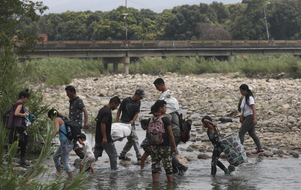 Venezuelans use the Tachira river as a crossing point on the Colombia and Venezuela border, with the Simon Bolivar International Bridge in the background, in La Parada, Colombia, Thursday, Feb. 28, 2019. The border between Colombia and Venezuela has been closed indefinitely by the Venezuelan government. (AP Photo/Martin Mejia)
