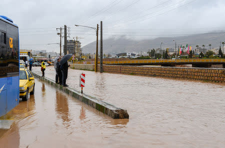 People stand near a flooded street after a flash flooding in Shiraz, Iran, March 26, 2019. Tasnim News Agency/via REUTERS