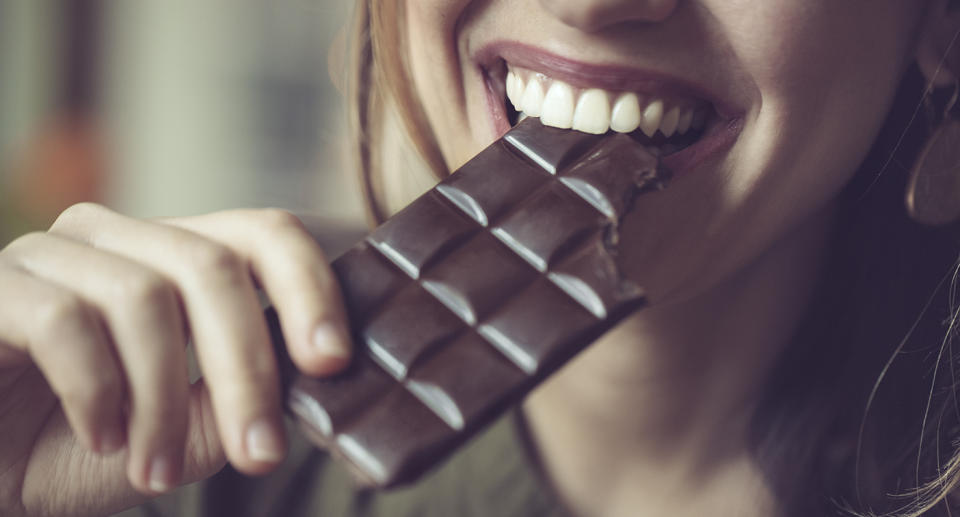 Woman biting into a chocolate bar.