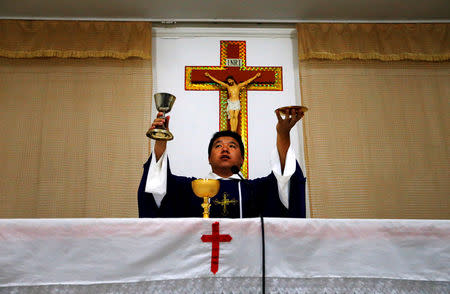 FILE PHOTO: Catholic priest Liu Yong Wang performs holy communion in a make-shift chapel in the village of Bai Gu Tun, located on the outskirts of the city of Tianjin, around 70 km (43 miles) south-east of Beijing July 17, 2012./File Photo