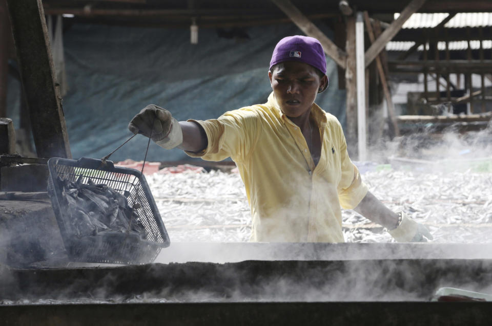 In this Thursday, Jan. 12, 2017 photo, a worker smokes dried fish for sale in a slum community on the coastal area of northern Jakarta, Indonesia. About 80 percent of the 3.6 billion people in developing Asian countries still live on less than $5 a day, many relying on day labor or other meager livelihoods. (AP Photo/Achmad Ibrahim, File)