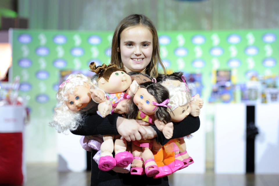 A little girl holding Cabbage Patch dolls