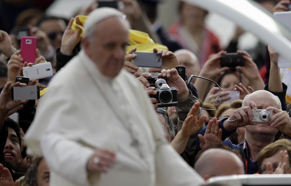 Faithful take pictures of Pope Francis touring St.Peter's Square aboard of his pope-mobile as he arrives for his general audience at the Vatican, Wednesday, April 9, 2014. (AP Photo/Gregorio Borgia)