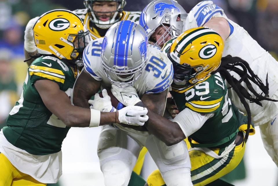Jamaal Williams of the Detroit Lions is tackled by De'Vondre Campbell (59) of the Green Bay Packers during the fourth quarter at Lambeau Field in Green Bay, Wisconsin, on Sunday, Jan. 8, 2023.