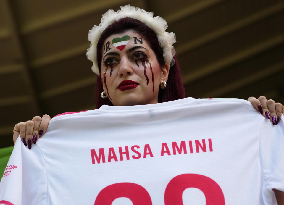 Una mujer muestra una camiseta con el nombre de Mahsa Amini, una mujer que murió tras ser detenida por la policía en Irán a los 22 años, en la grada antes del partido del Grupo B del Mundial entre Gales e Irán, en el estadio Ahmad Bin, en Rayán, Qatar, el 25 de noviembre de 2022. (AP Foto/Pavel Golovkin)