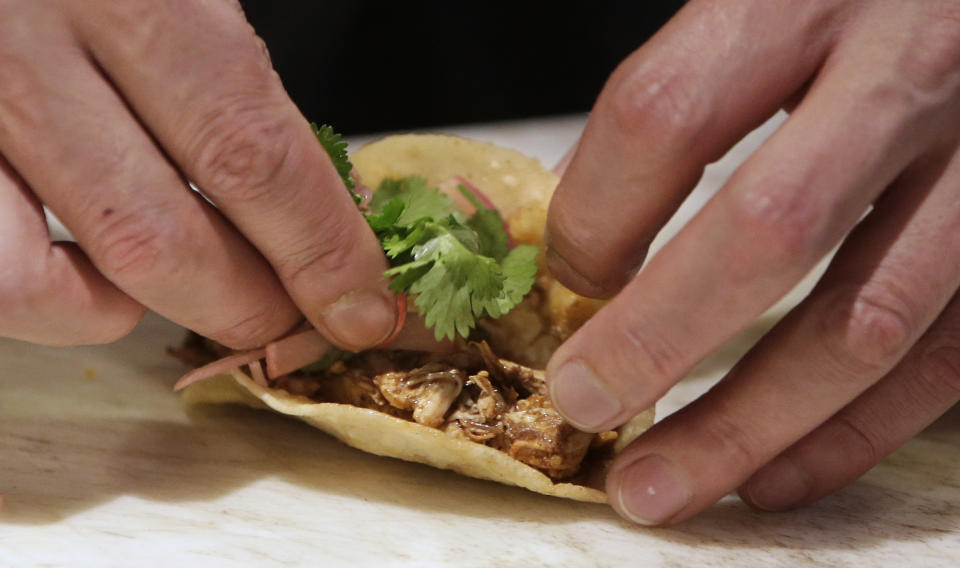 In this photo taken Tuesday, March 11, 2014, line cook Javier Rodriguez uses his bare hands to make chicken tacos at the Hock Farm restaurant in Sacramento, Calif. Under a bill signed last year by Gov. Jerry Brown, chefs and bartenders in California must keep bare hands off food going straight to the plate or the drink glass, and must use gloves or kitchen utensils such as tongs. California, where the law took effect Jan. 1 and will begin enforcement starting in July, will join 41 other states banning bare-hand contact with ready-to-eat food. In February,after receiving a petition from bartenders calling for an exemption for the "disposable glove law" the law's author, Assemblyman Richard Pan, D-Sacramento, a pediatrician, has introduced a bill to repeal the new regulation and revisit the entire issue.(AP Photo/Rich Pedroncelli)