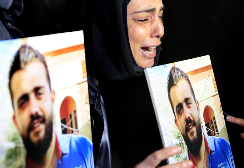 A mother of a victim of the Aug. 4, 2020 Beirut port explosion, cries as she holds a portrait of her son who killed during the explosion, during a sit-in outside the Justice Palace, in Beirut, Lebanon, Thursday, Feb. 18, 2021. Lebanon's highest court asked the chief prosecutor investigating last year's massive Beirut port explosion to step down, following legal challenges by senior officials he had accused of negligence that led to the blast, a judicial official and the country's official news agency said. (AP Photo/Hussein Malla)