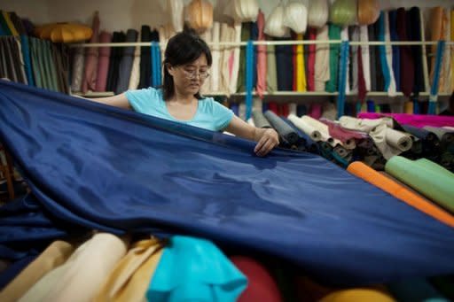 A vendor prepares rolls of silk at her textile and fabric shop in Beijing on July 19, 2012. China's economy will rebound in the second half of 2012 to achieve annual growth of eight percent as government policies to spur growth take effect, the International Monetary Fund said Wednesday