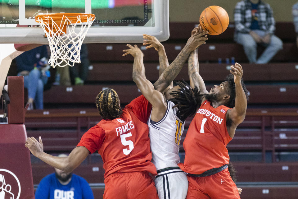Houston's Ja'Vier Francis (5) and Jamal Shead (1) challenge the shot of Towson's Mekhi Lowery (11) during the first half of an NCAA college basketball game in the Charleston Classic in Charleston, S.C., Thursday, Nov. 16, 2023. (AP Photo/Mic Smith)
