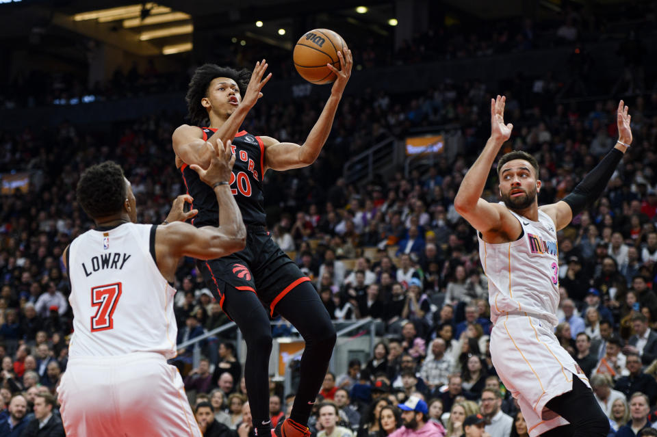 Toronto Raptors guard Jeff Dowtin Jr. (20) drives between Miami Heat guard Kyle Lowry (7) and guard Max Strus (31) during the first half of an NBA basketball game in Toronto on Tuesday, March 28, 2023. (Christopher Katsarov/The Canadian Press via AP)