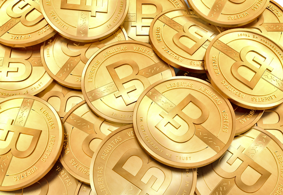 A pile of glittering gold coins, all embossed with the Bitcoin logo