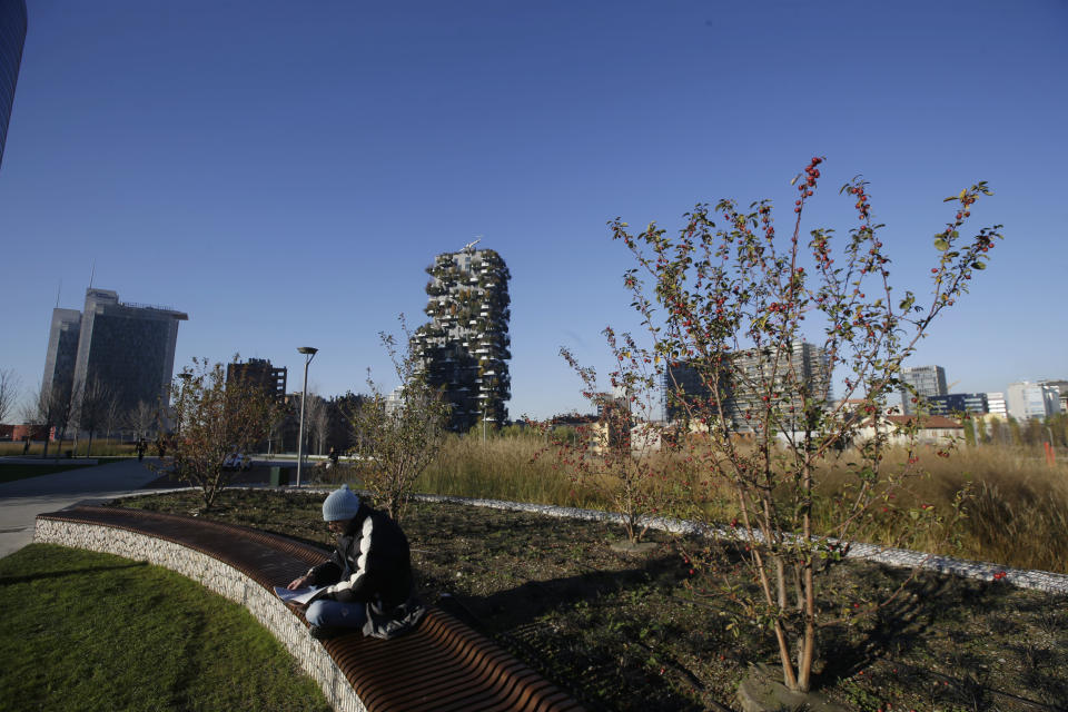 In this picture taken on Tuesday, Dec. 4, 2018 a man relaxes as he sits on a bench at the Tree Library park in Milan, Italy. If Italy's fashion capital has a predominant color, it is gray not only because of the blocks of uninterrupted neoclassical stone buildings for which the city is celebrated, but also due to the often-gray sky that traps in pollution. The city has ambitious plans to plant 3 million new trees by 2030_ a move that experts say could offer relief to the city’s muggy and sometimes tropical weather. (AP Photo/Luca Bruno)