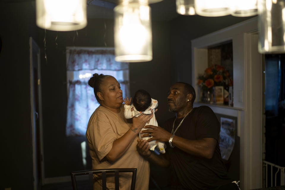 Krista, left, and Navada Gwynn look after a friend's baby, 2-month-old Katelia, at their home in Louisville, Ky., Tuesday, Aug. 29, 2023. The Gwynns' son, Christian, was shot and killed in 2019, the same year Katelia's uncle was shot and killed in a restaurant argument. Two years later, the Gwynns' daughter, Victoria, was shot and injured while sitting in a park. (AP Photo/David Goldman)