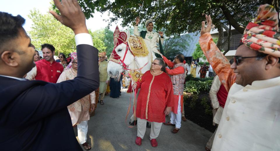 During the baraat, Anup Kumar Kanodia enjoys friends and family dancing while he is on a white horse. The baraat is a traditional Indian ritual symbolizing a groom arriving from a neighboring village for the wedding with his bride.