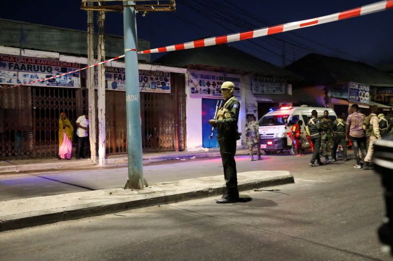 Somali security officers secure the scene of a car bomb explosion as paramedics await to rescue the injured in the Kilometre 4 area of Mogadishu