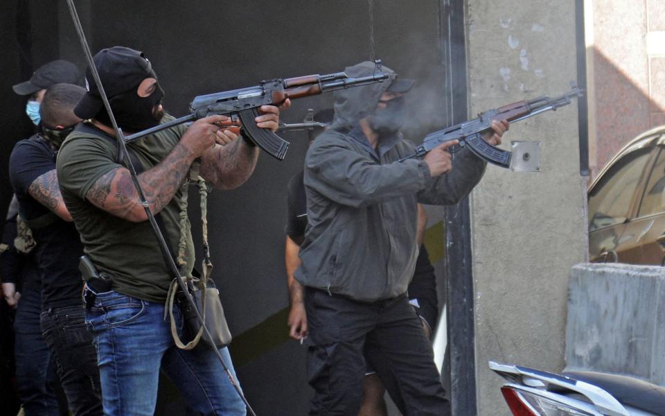 Shiite fighter from Hezbollah and Amal movements take aim with Kalashnikov