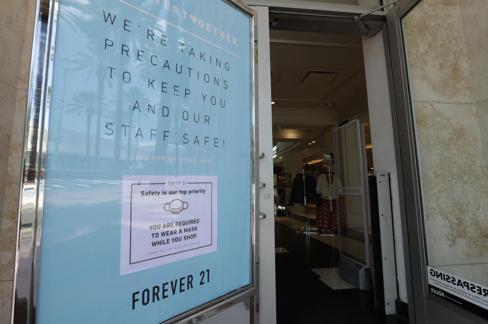 A sign outside a Forever 21 store in Miami Beach, advises shoppers that they must wear a mask to protect against the new coronavirus when entering the store. - Credit: AP