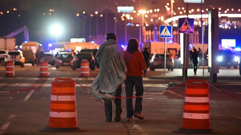 A couple walk near the Crocus City Hall on the western edge of Moscow, Russia, Friday, March 22, 2024.