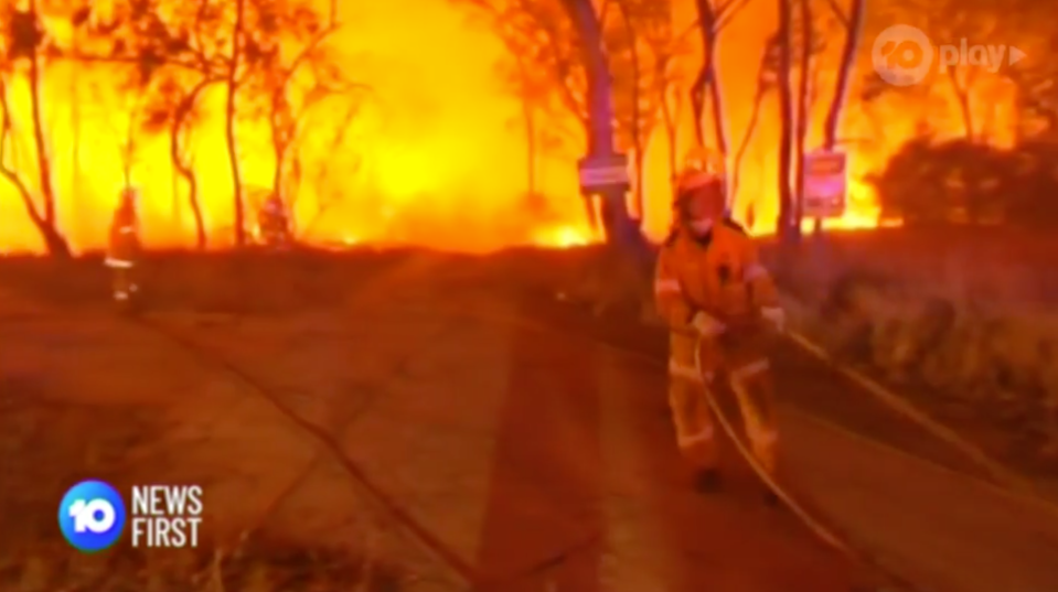 A firefighter drags a hose under darkness in NSW's New England region.
