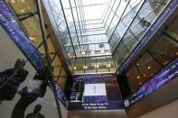 People pass electronic information boards at the London Stock Exchange in the City of London October 11, 2013. REUTERS/Stefan Wermuth