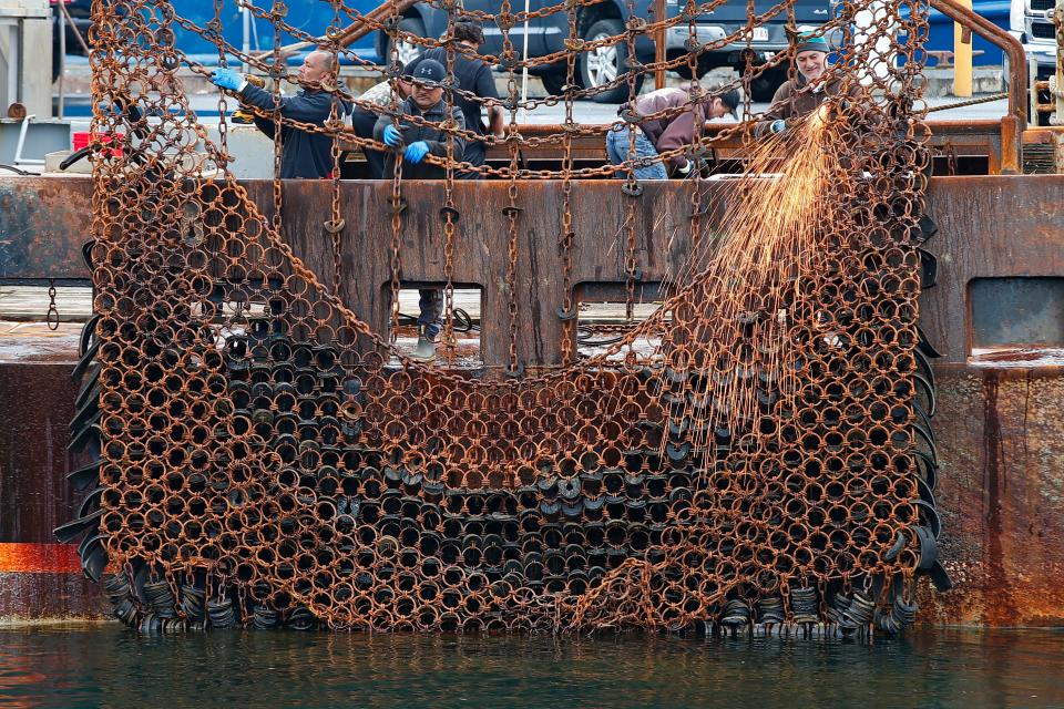 Fishermen make repairs to the dredges of a scalloper docked in New Bedford.