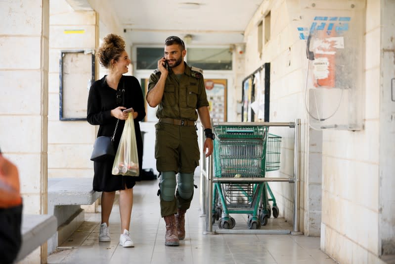 FILE PHOTO: An Israeli soldier and a woman chat as they walk past shops in the Israeli settlement of Ofra in the occupied West Bank