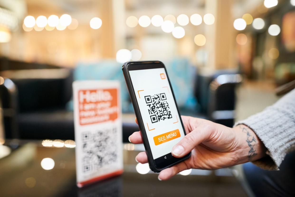 Close-up of hand of a woman scanning the qr code with her phone to make a cashless payment in a cafe