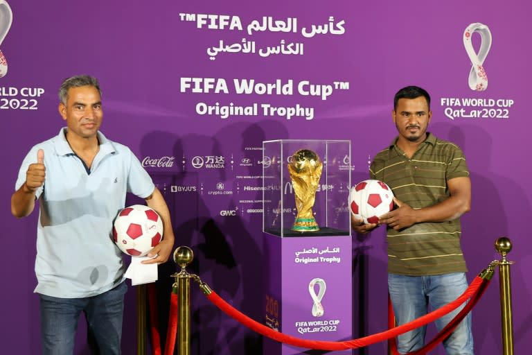Foreigners pose next to the World Cup trophy in Doha for an event marking 200 days until the 2022 tournament (AFP/KARIM JAAFAR)