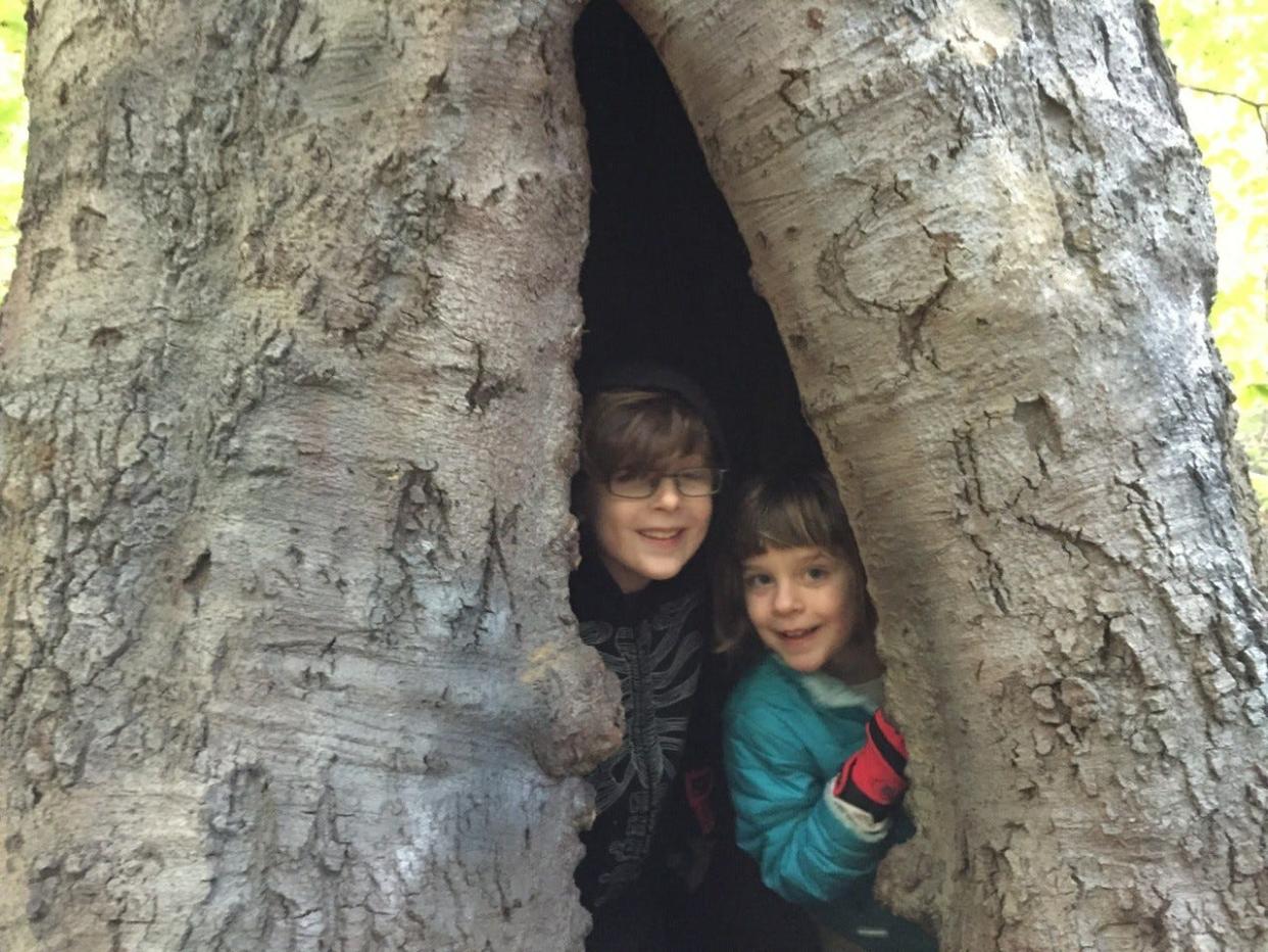 Gabriel Hutnick, left, and Heidi Jacobs enjoy hiding inside the trunk of the American Beech, or Emancipation Tree, in Saddler's Woods, before it fell on June 3, 2020, during a thunderstorm,