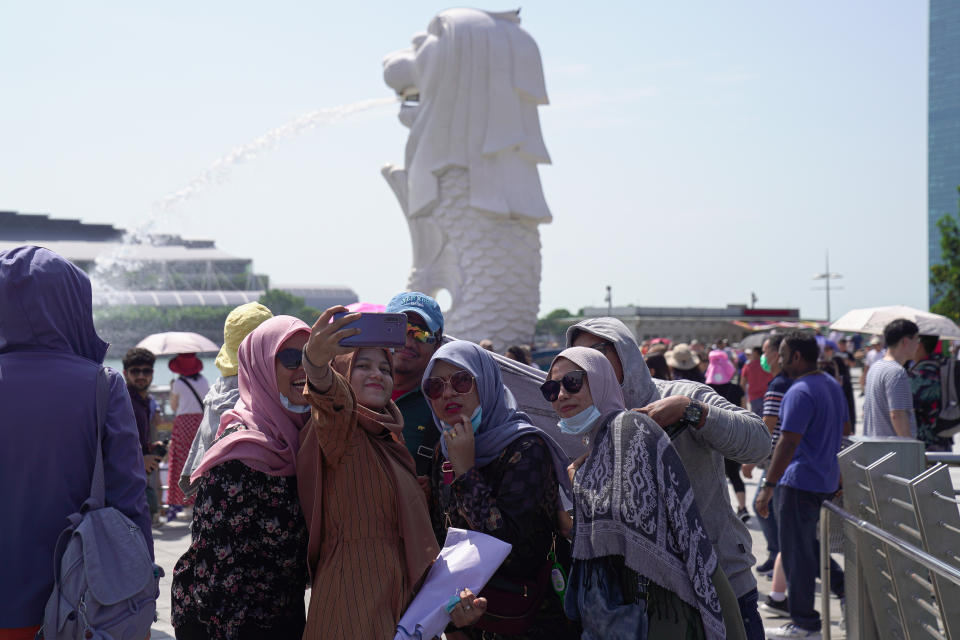 SINGAPORE, SINGAPORE - JANUARY 26: Visitors wearing masks take a selfie on a phone at the Merlion Park on January 26, 2020 in Singapore. Singapore has confirmed four cases of the deadly coronavirus, which emerged last month in the city of Wuhan in China. (Photo by Ore Huiying/Getty Images)