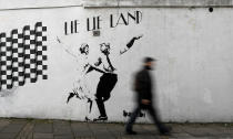 <p>A pedestrian passes a new piece of art by street artist Bambi in London. in London, eb. 16, 2017. The work, entitled Lie Lie Land, features a dancing British Prime Minister Theresa May and President Donald Trump in the pose made famous by the movie La La Land. (Photo: Kirsty Wigglesworth/AP) </p>
