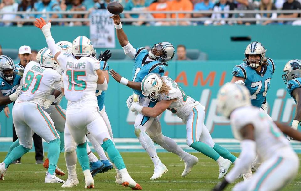 Carolina Panthers quarterback Cam Newton, center, is sacked by Miami Dolphins Andrew Van Ginkel, right, on a pass attempt during the second quarter at Hard Rock Stadium in Miami Gardens, Fla. on Sunday, November 28, 2021.