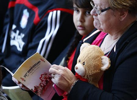 A woman reads a programme during a memorial service to mark the 25th anniversary of the Hillsborough disaster at Anfield in Liverpool, northern England April 15, 2014. REUTERS/Darren Staples