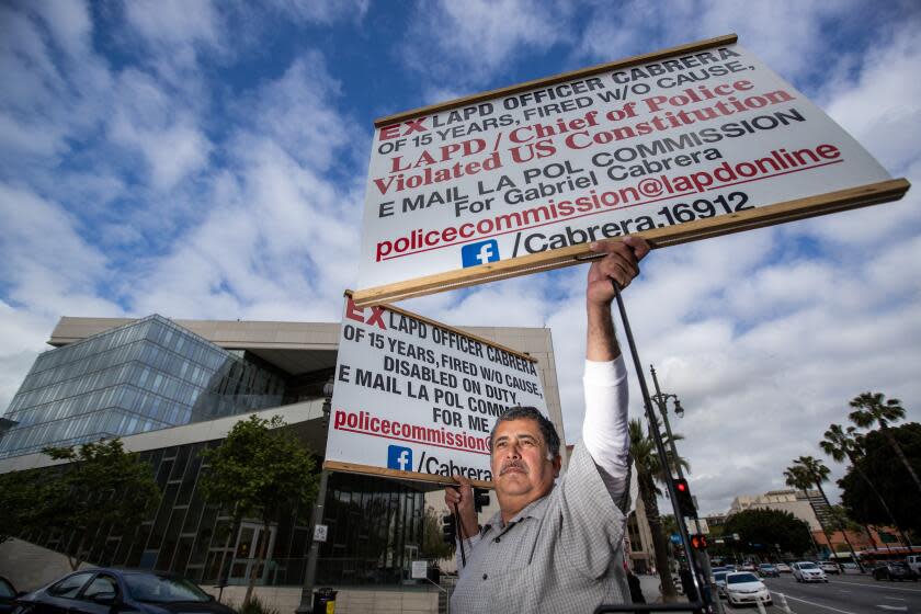 Los Angeles, CA - May 02: Gabriel Cabrera, who was fired from his job as an LAPD officer, makes a solemn protest with his homemade signs every Tuesday outside of the downtown Los Angeles police headquarters, asking for his job back for the past year or so. He says he is the victim of the department's long history of disability discrimination and maintains that the union and former friends have all turned their backs on him. He's had to take a job working security at Disneyland, and rent out the top floor of his home in order to make ends meet. The stress of the ordeal likely led to his wife having a stroke and nearly cost him his marriage. Still, he shows up almost every Tuesday morning with new handmade signs, to picket outside police headquarters. Photos taken in in Los Angeles Tuesday, May 2, 2023. (Allen J. Schaben / Los Angeles Times)