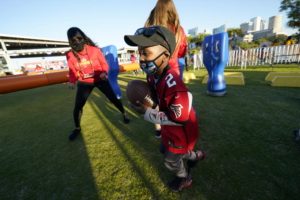 Isaiah Sheppard, 7, runs with a football at the NFL Experience for Super Bowl LV Friday, Jan. 29, 2021, in Tampa, Fla. (AP Photo/David J. Phillip)