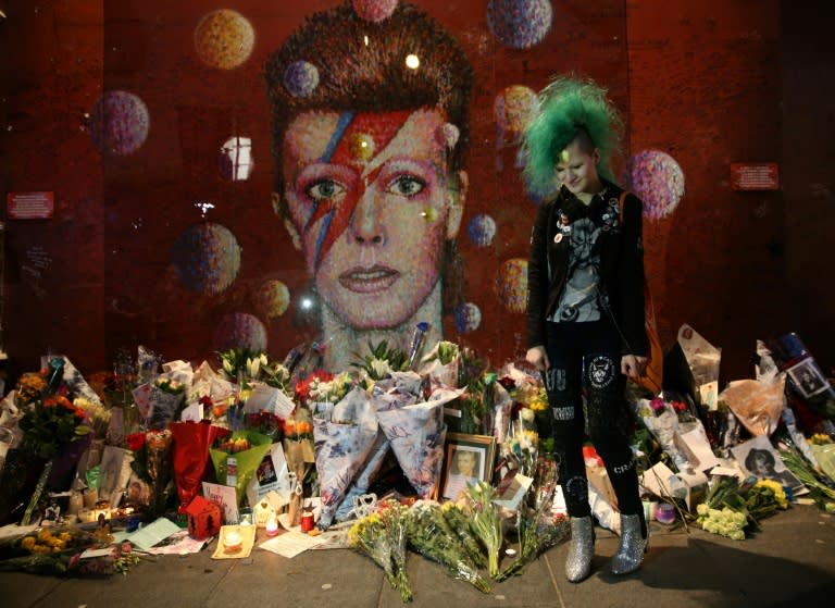 A David Bowie fan poses in front of the mural of the late British pop icon created by Australian street artist James Cochran, also known as Jimmy C, as fans payed their respects in Brixton, south London