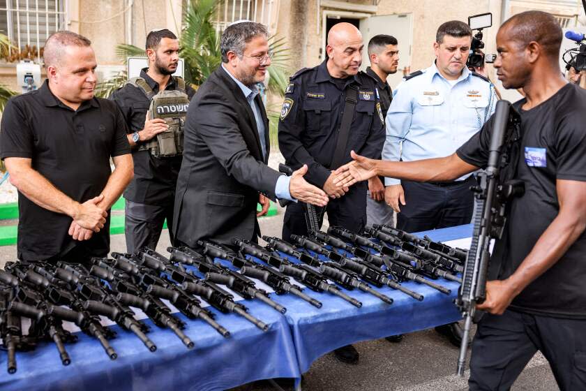 Israel's National Security Minister Itamar Ben-Gvir (C-L) shakes hands with a volunteer of the new civilian guard unit while handing out M5 automatic assault rifles, during the unit's inauguration ceremony in the southern city of Ashkelon on October 27, 2023. (Photo by Menahem KAHANA / AFP) (Photo by MENAHEM KAHANA/AFP via Getty Images)