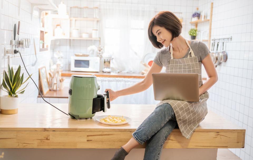 a woman cooking with an air fryer in a kitchen