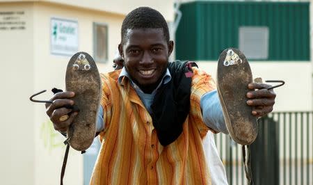 An African migrant shows off cleated shoes used for climbing the border fence after arriving at the CETI, the short-stay immigrant centre, after crossing the border from Morocco to Spain's North African enclave of Melilla, Spain, June 26, 2016. REUTERS/Jesus Blasco de Avellaneda