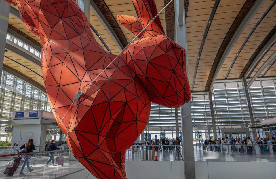 Travelers check in under the watchful eye of “Leap,” the red rabbit sculpture by Lawrence Argent, at Sacramento International Airport’s Terminal B on Nov. 22, 2023, the day before Thanksgiving.