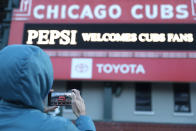 A person takes a photo of the Wrigley Field marquee, early morning on the opening day baseball game between the Chicago Cubs and the Pittsburgh Pirates, Thursday, April 1, 2021 at Chicago. From New York to Seattle and everywhere in between, it’s a much different opening day in 2021. Fans are back at the ballpark after they were shut out during the regular season last year because of the coronavirus pandemic. (AP Photo/Shafkat Anowar)