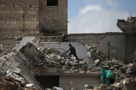 A boy walks over rubble of damaged buildings in the northern Syrian city of al-Bab, Syria March 13, 2017. REUTERS/Khalil Ashawi