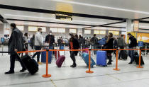 FILE - In this Dec. 20, 2020, file photo, passengers queue for check-in at Gatwick Airport in West Sussex, England, south of London. The United States will require airline passengers from Britain to get a negative COVID-19 test before their flight, the Centers for Disease Control and Prevention announced late Thursday, Dec. 24. The U.S. is the latest country to announce new travel restrictions because of a new variant of the coronavirus that is spreading in Britain. (Gareth Fuller/PA via AP)