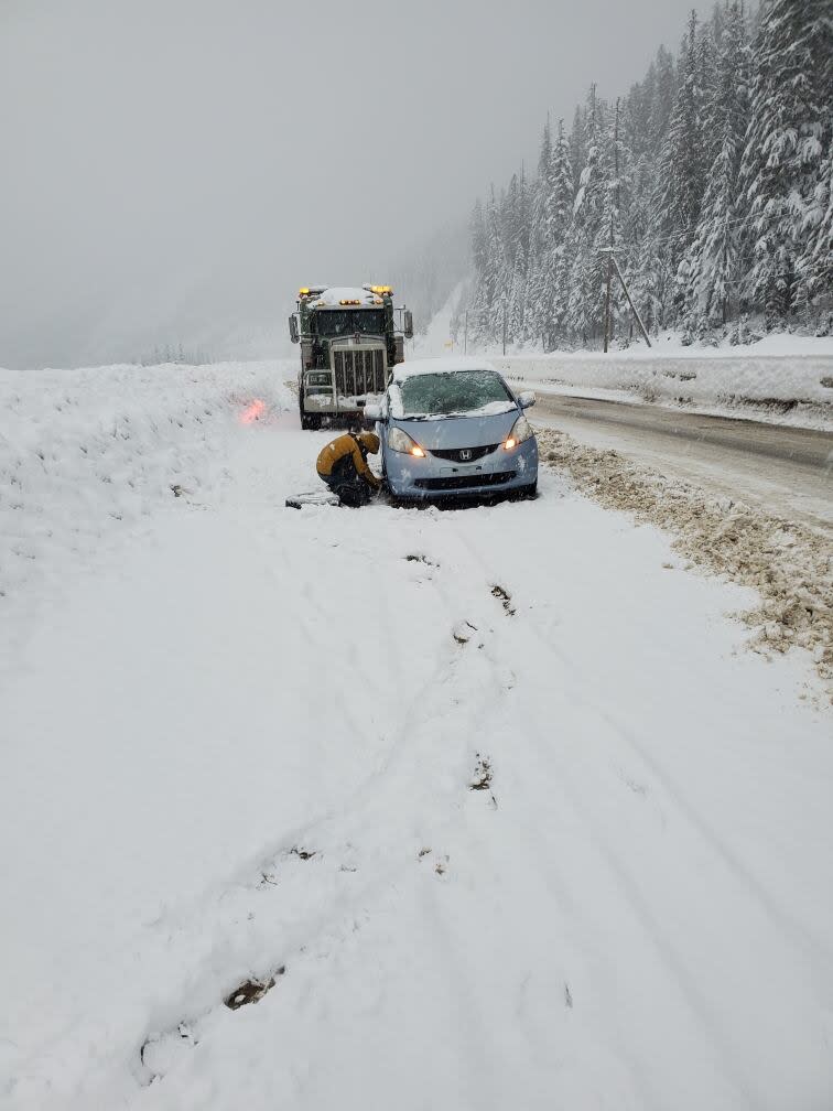 A traveler on the Coquihalla Highway changes a tire during a snow storm on Feb. 28, 2024.
