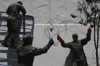 Solsiers removes ribbons of razor wire from the perimeters of Carondelet Palace, the seat of government, in Quito Ecuador, Monday, Oct. 14, 2019. Cleanup of the capital began hours after President Lenín Moreno and indigenous leaders struck a deal late Sunday to cancel a disputed austerity package and end nearly two weeks of protests that paralyzed the Ecuadorian economy and left seven dead. (AP Photo/Dolores Ochoa)