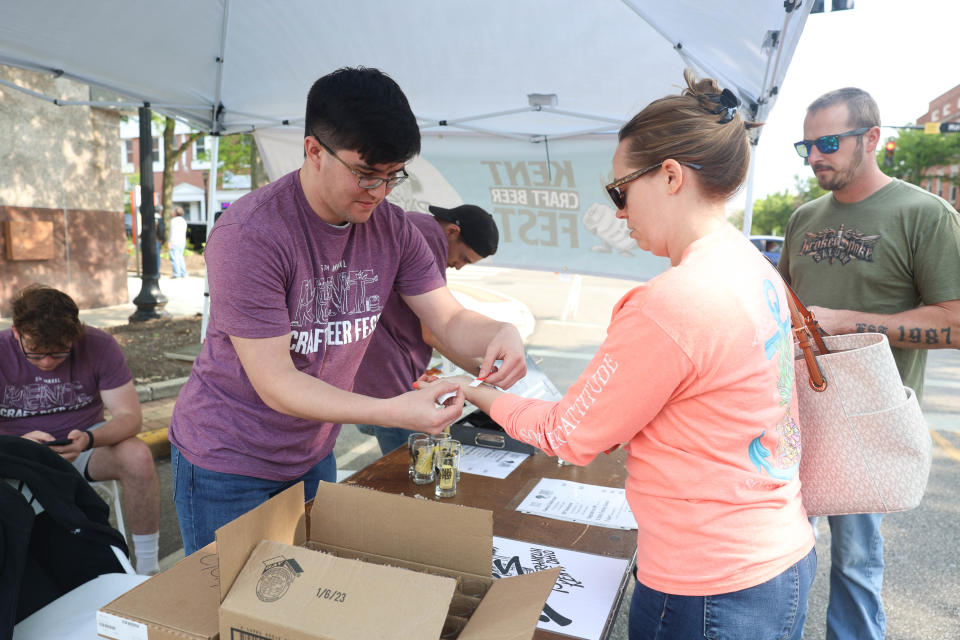 Volunteer Gabriel McKernan puts wristbands on attendees to the fifth annual Kent Jaycees Craft Beer Fest as they enter to begin tasting beers from 27 breweries.