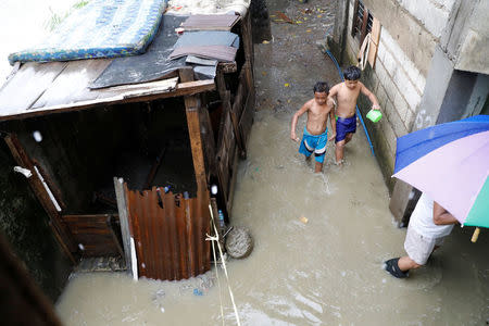 Residents walk near the site (left side with a police makeshift line) where Kian Loyd delos Santos, a 17-year-old high school student, who was among the people shot dead last week in an escalation of President Rodrigo Duterte's war on drugs in Caloocan city, Metro Manila, Philippines August 21, 2017. REUTERS/Erik De Castro