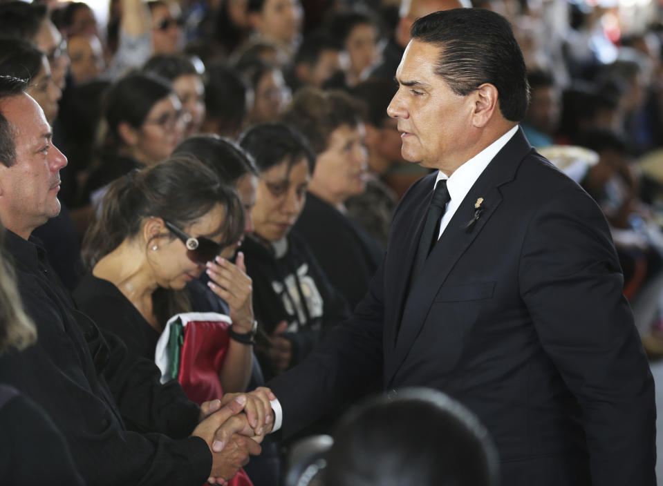 El gobernador del estado mexicano de Michoacán, Silvano Aureoles, estrecha la mano de un familiar de un policía que fue asesinado en una aparente emboscada, durante un funeral en Morelia, México, el martes 15 de octubre de 2019. (AP Foto/Marco Ugarte)