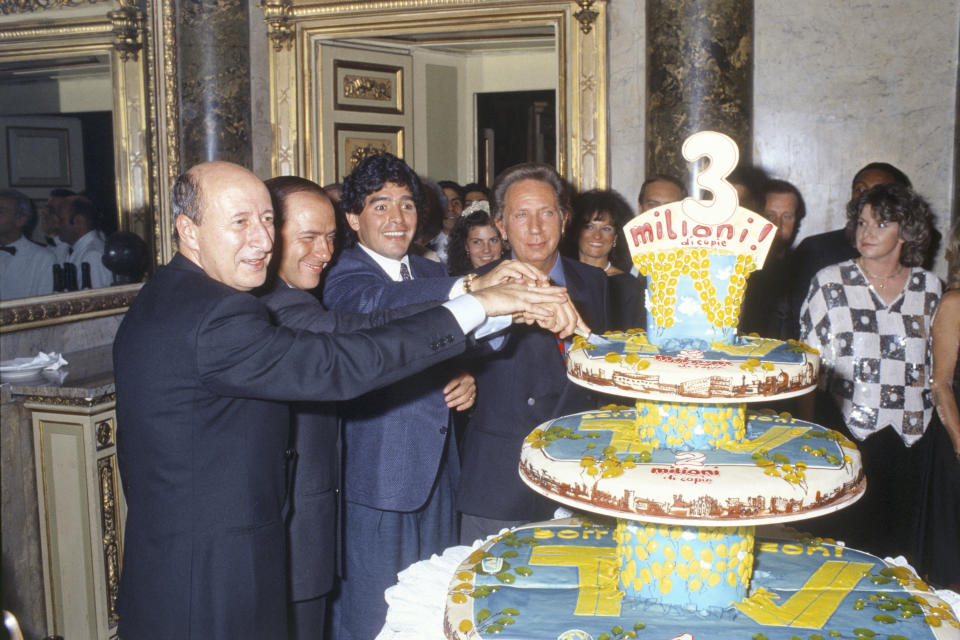 Junto a Silvio Berlusconi y a los periodistas italianos Gigi Vesigna y Mike Bongiorno, El Pelusa corta una tarta en una fiesta organizada por la revista ‘TV Sorrisi e Canzoni’. (Foto: Angelo Deligio / Mondadori / Getty Images).